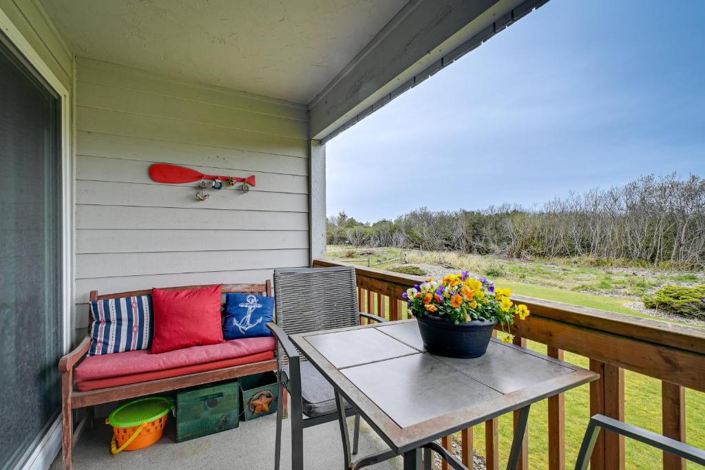 a porch with a bench and a table with flowers at Ocean Shores Condo with Balcony Less Than 1 Mi to Beach! in Ocean Shores
