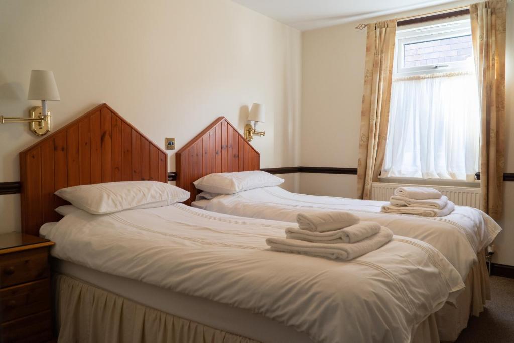 two beds in a room with towels on them at The Olde Ship Inn in Seahouses