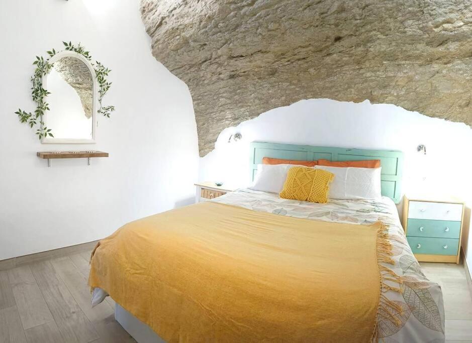 ein Schlafzimmer mit einem Bett mit einer Steinmauer in der Unterkunft Casa Cueva La Luna in Setenil de las Bodegas