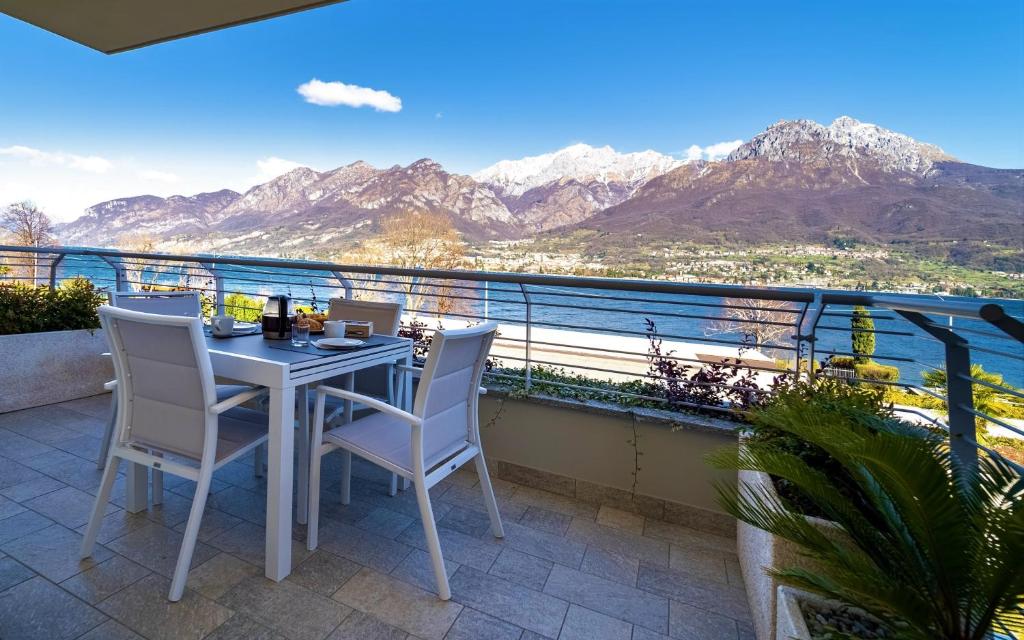 a table and chairs on a balcony with mountains at Mughetto Apartment in Oliveto Lario
