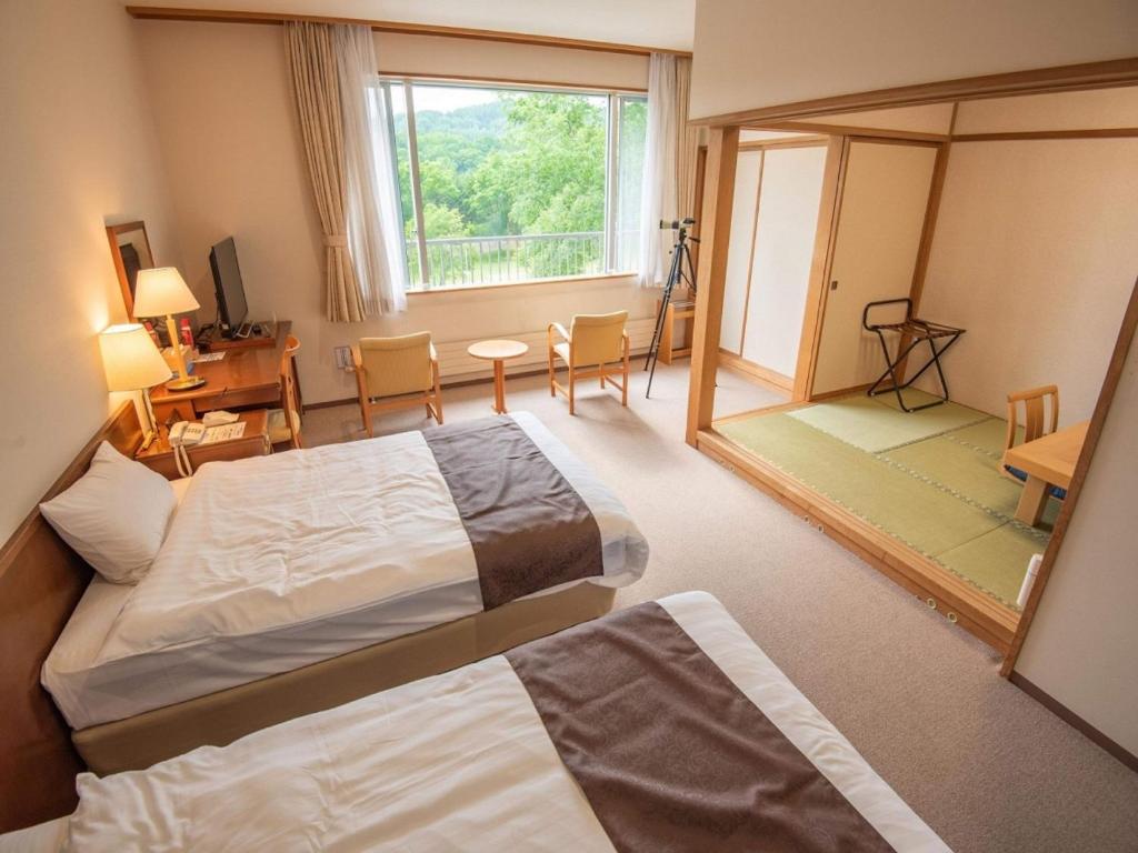 um quarto de hotel com duas camas e uma grande janela em Japanese Auberge Plaza Ryokufu Natural Hot Spring - Vacation STAY 03265v em Shimo-orube