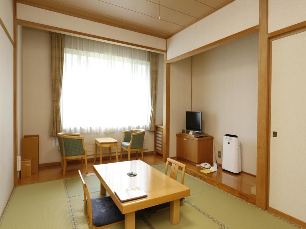 a room with a table and chairs and a television at Japanese Auberge Plaza Ryokufu Natural Hot Spring - Vacation STAY 03218v in Shimo-orube