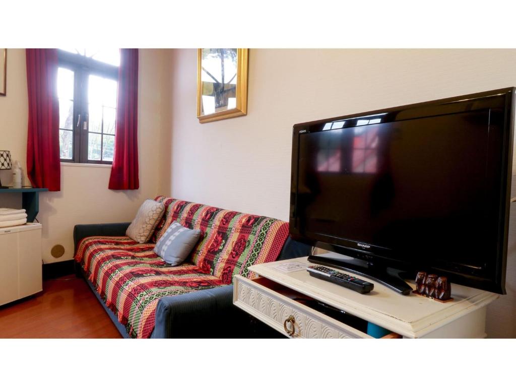 ein Wohnzimmer mit einem Sofa und einem Flachbild-TV in der Unterkunft Nikko Park Lodge - Vacation STAY 15295v in Nikko
