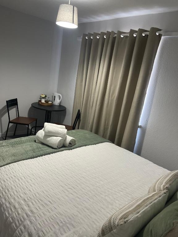 a bedroom with a bed with white sheets and a curtain at cozy room Shared House in Bristol