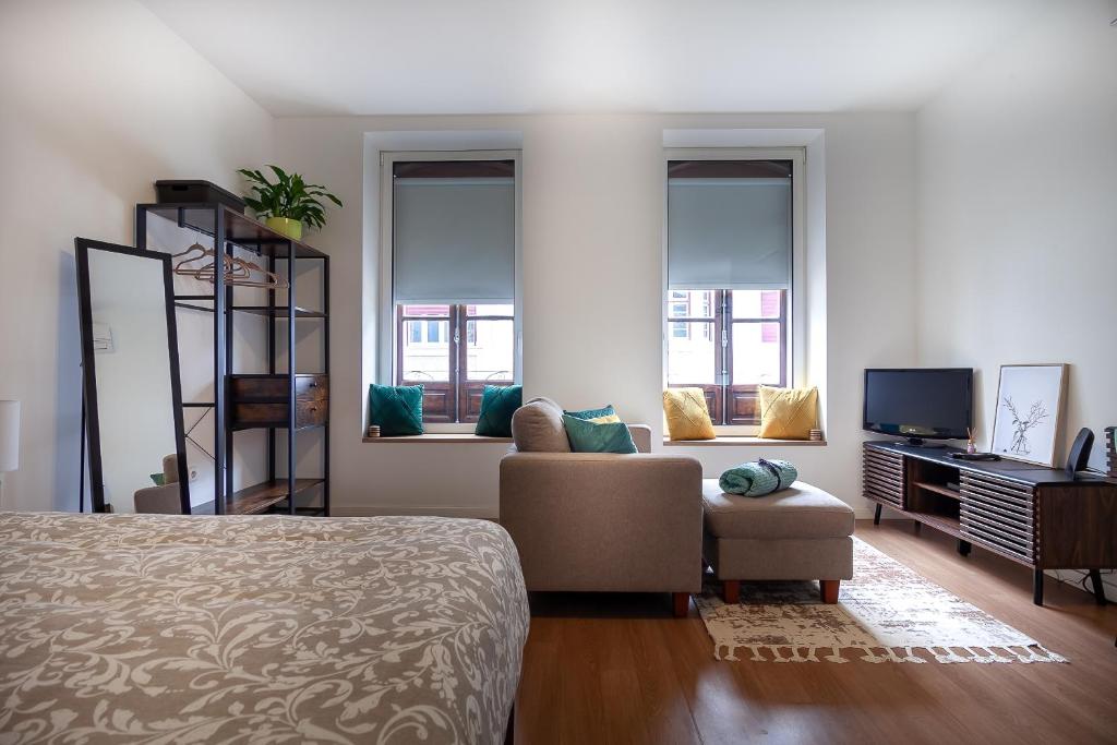 a bedroom with a bed and a couch and windows at Casa Esmeralda by Home Sweet Home Aveiro in Aveiro