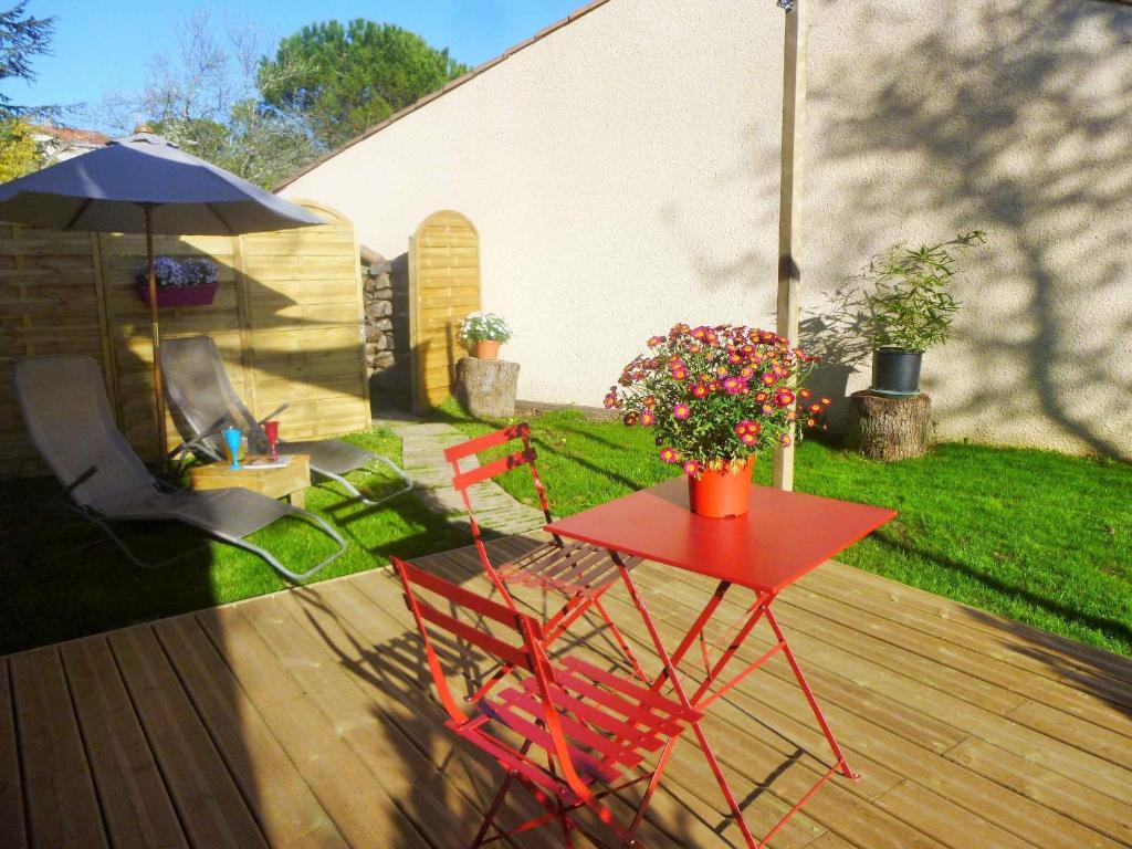 una mesa roja y sillas en una terraza con sombrilla en Chambre d'hôtes "Mirabel", en Saint Jean