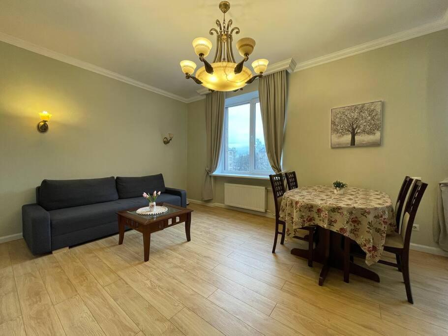 a living room with a couch and a table and a chandelier at Eksporta Street Quiet Old Riga Apartment in Rīga