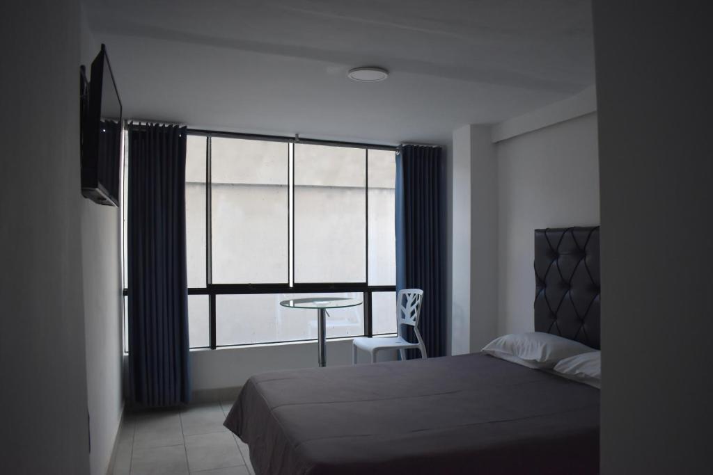 1 dormitorio con cama, mesa y ventana en Hotel Demetria, en Huánuco