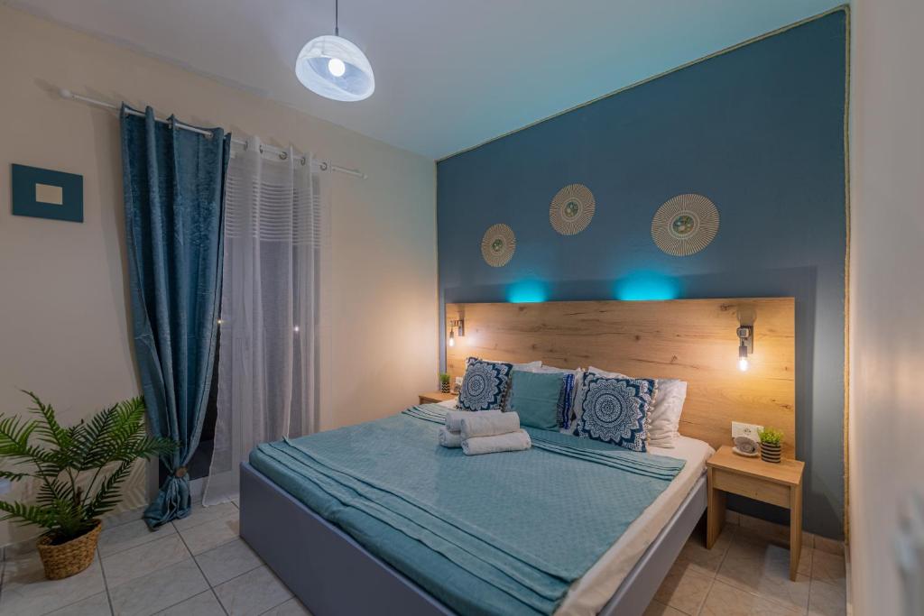 a bedroom with a large bed with a blue headboard at Sarita's Apartments & Suite in Laganas