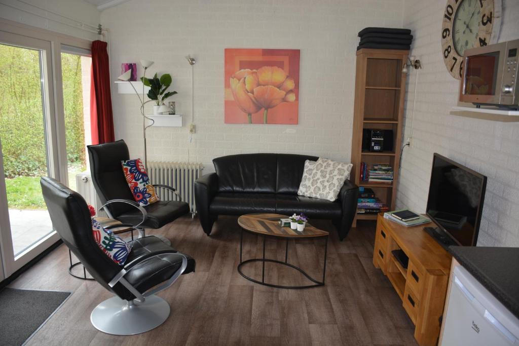 een woonkamer met een zwarte leren bank en stoelen bij Vakantiehuis Rosa in Simpelveld