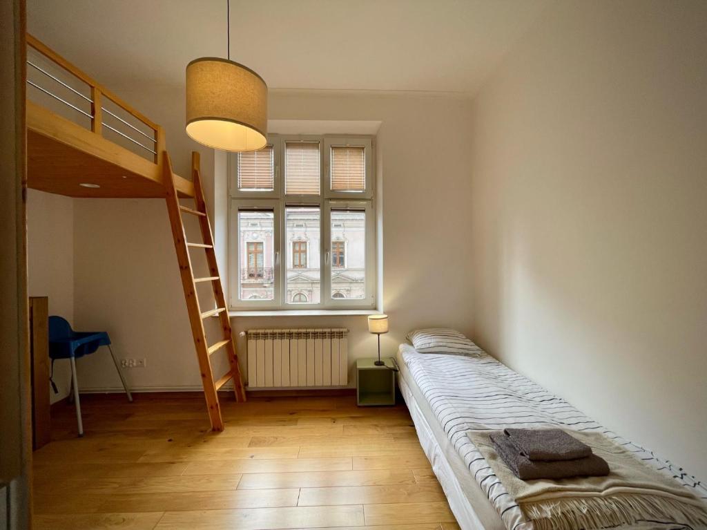 1 dormitorio con cama, escalera y ventana en Apartamenty Zasanie, en Przemyśl