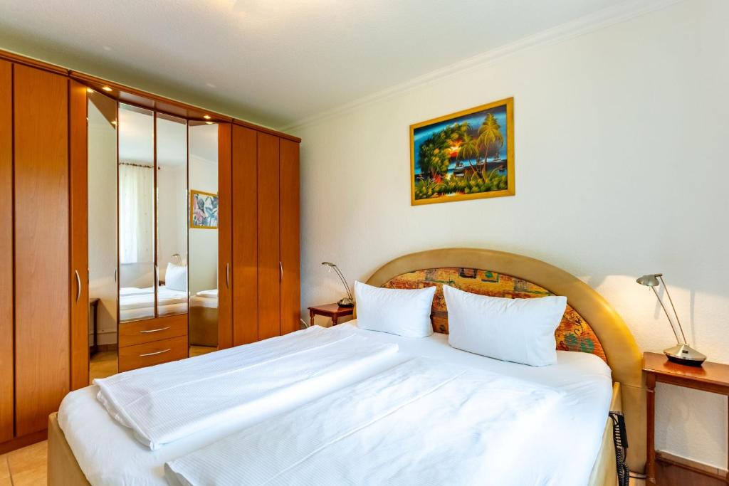 1 Schlafzimmer mit einem großen weißen Bett und einem Badezimmer in der Unterkunft Ferienwohnung Juliane in der Villa zum Kronprinzen direkt gegenüber der Saarow Therme in Bad Saarow