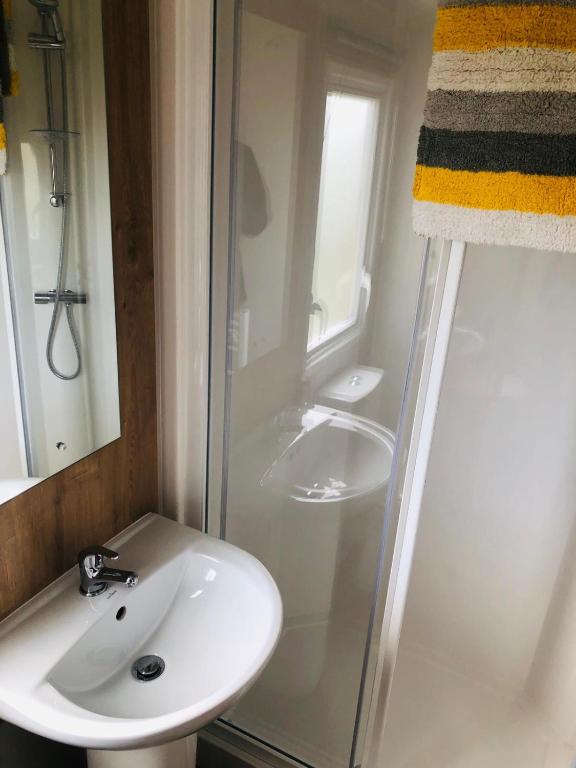 a white bathroom with a sink and a shower at Cosy holiday home at Romney Sands in New Romney