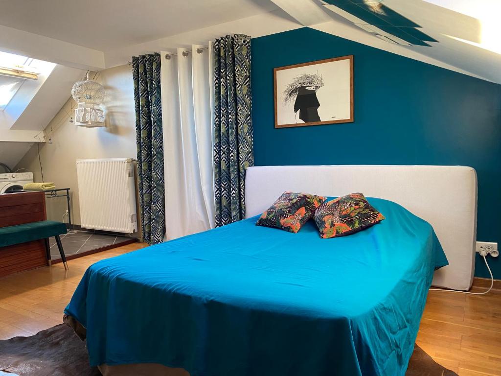 - une chambre avec des murs bleus et un lit avec deux oreillers dans l'établissement Maison Auguste, à Meyzieu