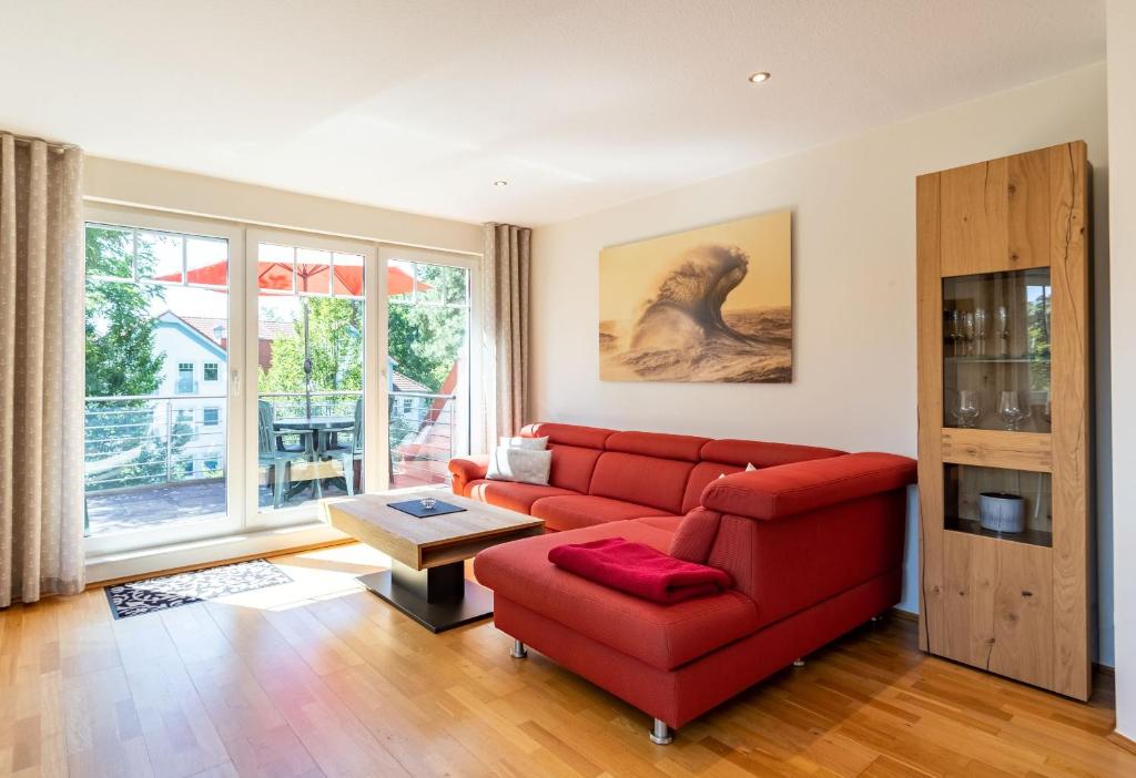 uma sala de estar com um sofá vermelho e uma mesa em Ferienwohnung Christiane in der Villa zum Kronprinzen direkt gegenüber der SaarowTherme em Bad Saarow