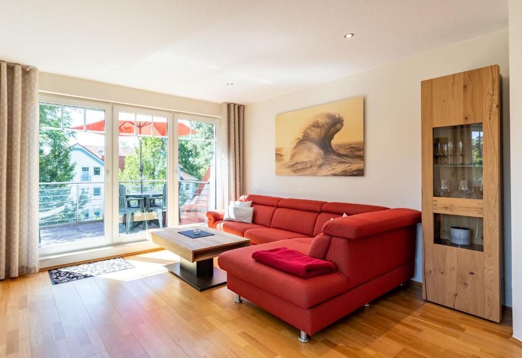 a living room with a red couch and a table at Ferienwohnung Christiane in der Villa zum Kronprinzen direkt gegenüber der SaarowTherme in Bad Saarow