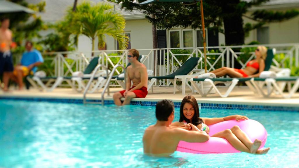 um grupo de pessoas em uma piscina com uma jangada rosa em Bay View Suites Paradise Island em Nassau