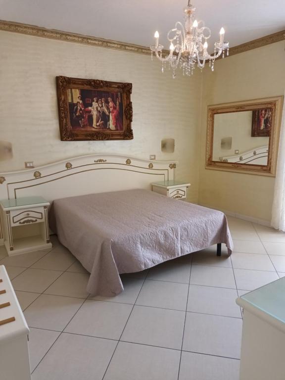 una camera con letto, specchio e lampadario a braccio di DIO DEL MARE LUXURY ROOM a Porto Cesareo
