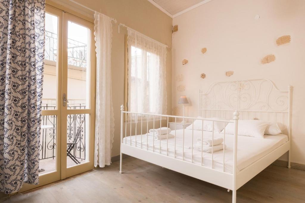 a white bedroom with a bed and a balcony at Iliotropio Art in Chania Town