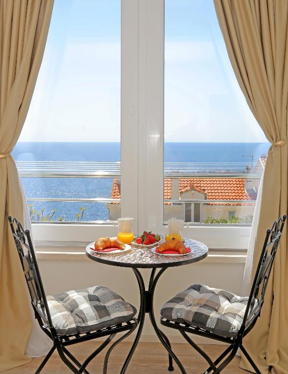 a table with a plate of food and two chairs in front of a window at Blue Cliff Apartment in Dubrovnik