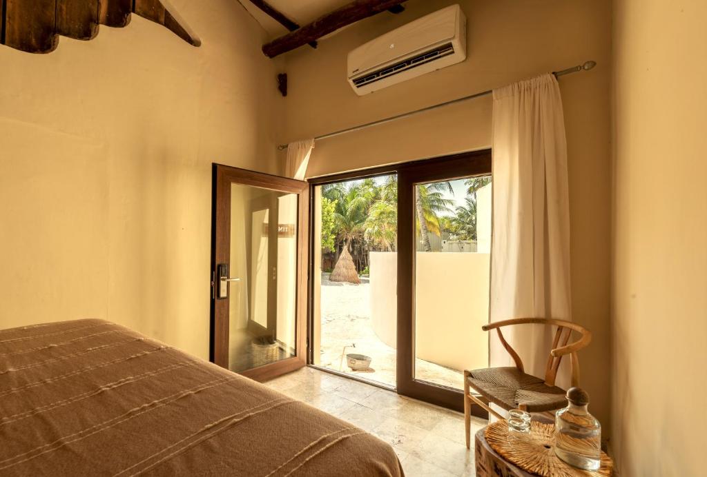 a bedroom with a bed and a sliding glass door at Alquimia Hotel Boutique in Tulum