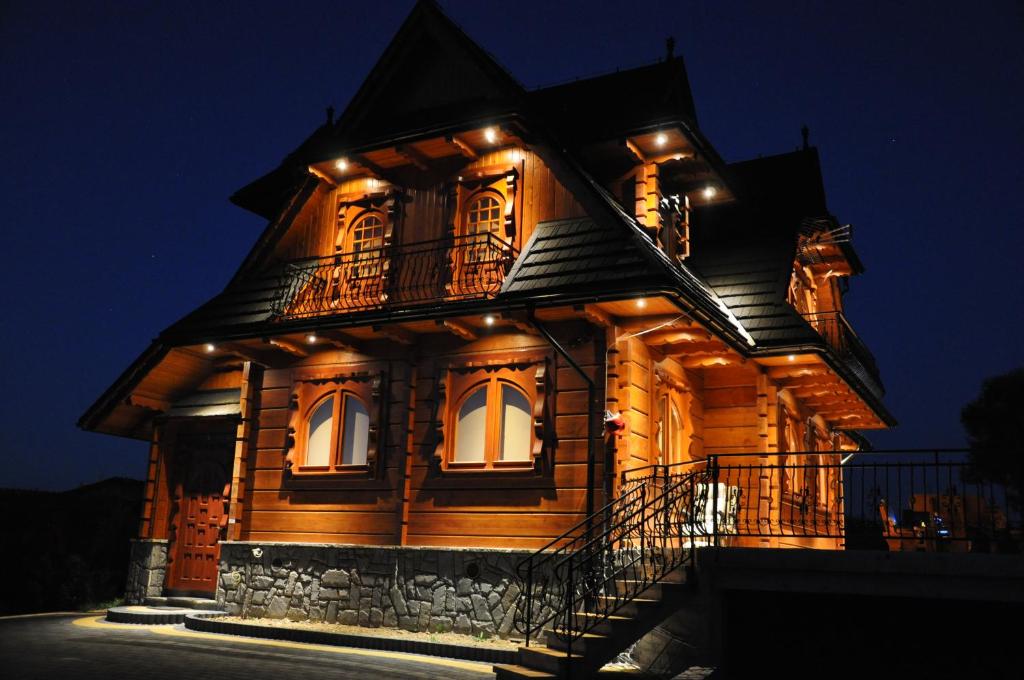 a large wooden house with lights on it at night at Szaflary Dom in Szaflary