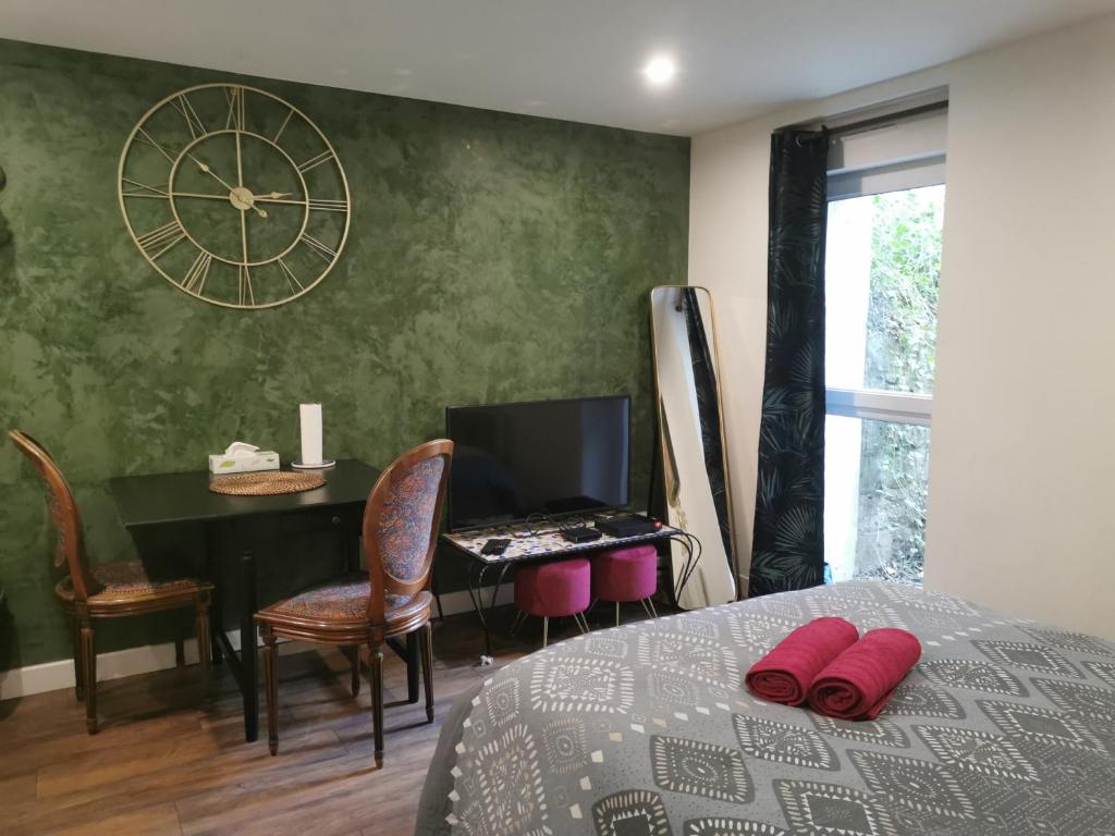 a bedroom with a bed and a desk with a clock on the wall at Green Cellar studio Centre de Strasbourg - 5 min conseil de l'Europe in Strasbourg