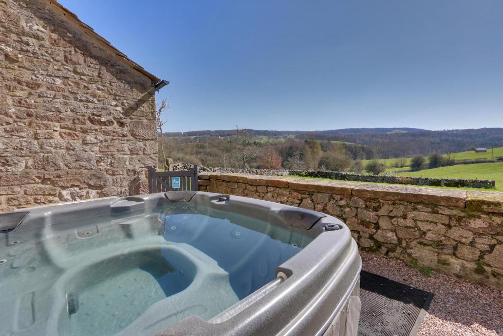 een hot tub voor een stenen gebouw bij Derbyshire Chapel for 6 at Harthill Hall private hot tub 8am - 10pm plus private daily use of indoor pool and sauna 1 hour in Stanton in Peak