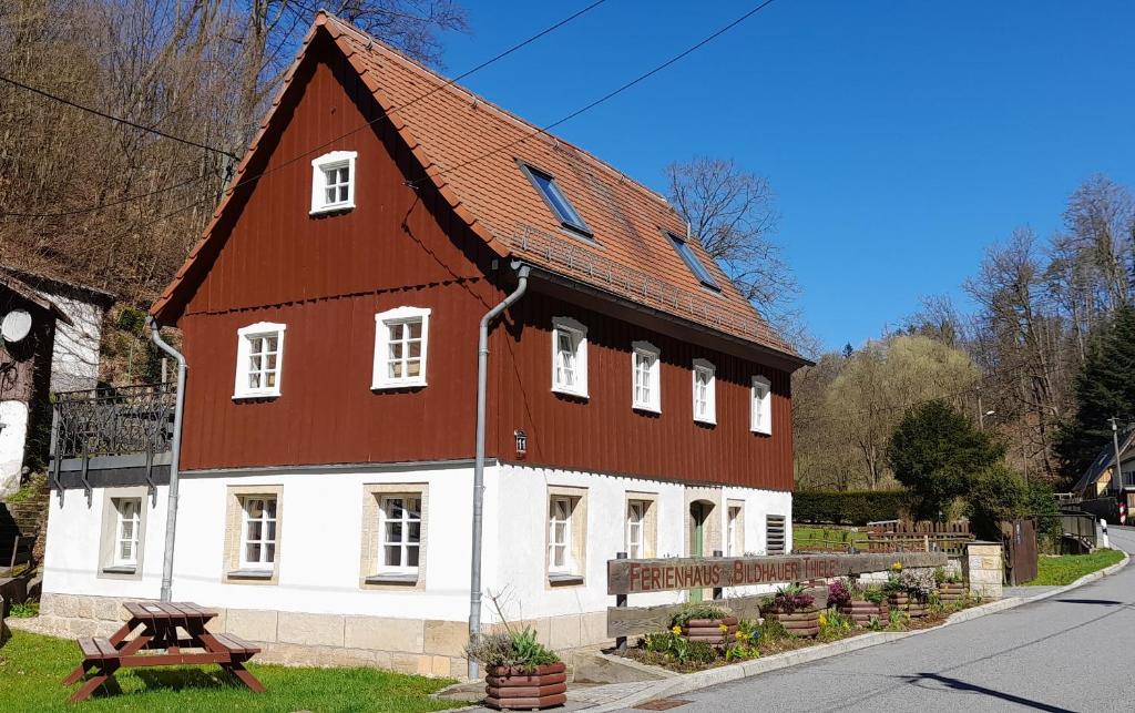 duży brązowo-biały budynek z drewnianym dachem w obiekcie Ferienhaus Bildhauer Thiele w mieście Ottendorf