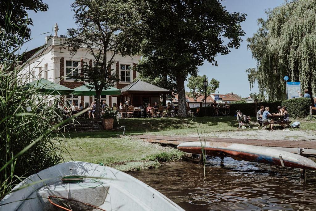 un barco sentado en el agua junto a una casa en Hotel Prinz Heinrich en Werder