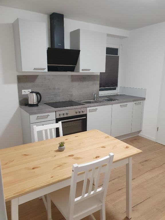 a kitchen with a wooden table and white cabinets at Apartments am Kochertal in Oedheim