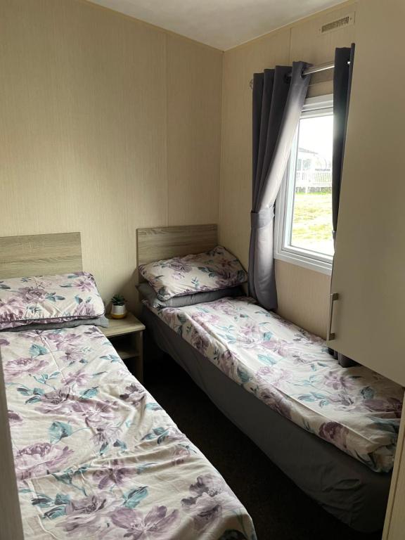 twee bedden in een kleine kamer met een raam bij 9 shearwater Tattershall Lakes Country Park in Tattershall