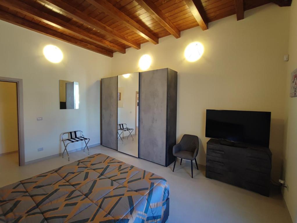 イーゾラ・デル・リーリにあるIN CENTRO Rooms and Apartmentsのベッドルーム(ベッド1台、テレビ、椅子付)