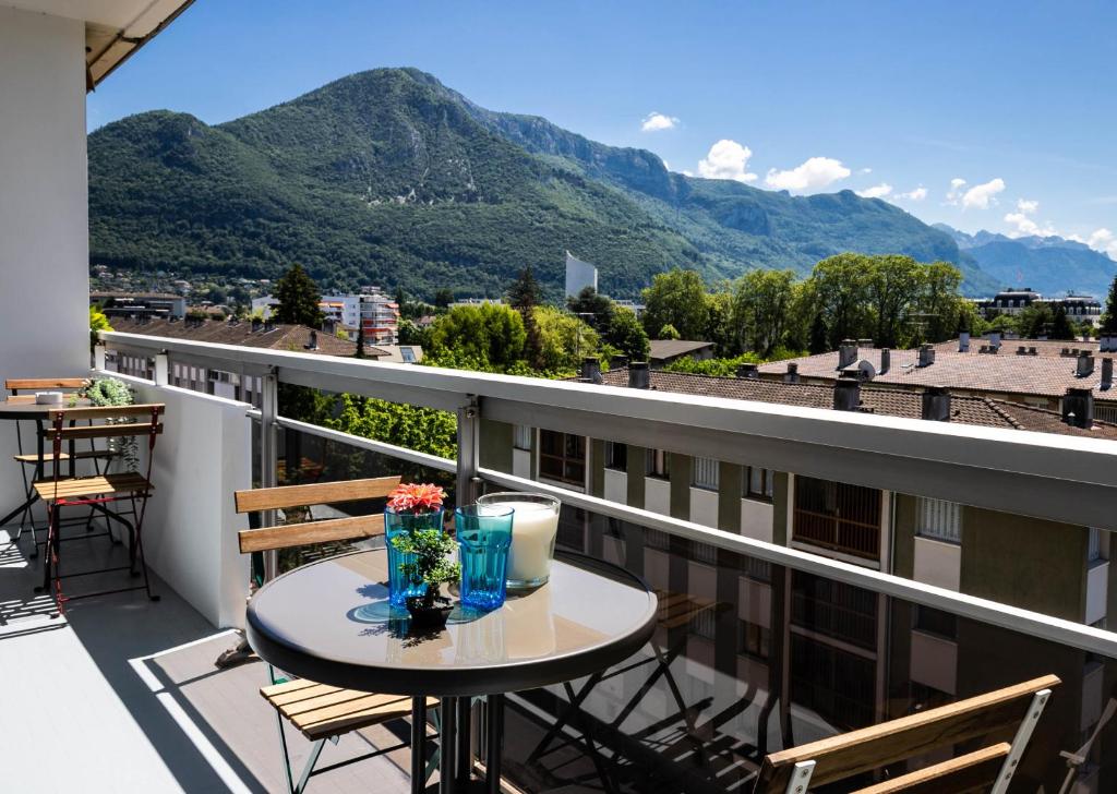 d'un balcon avec une table, des chaises et des montagnes. dans l'établissement Hysope, à Annecy
