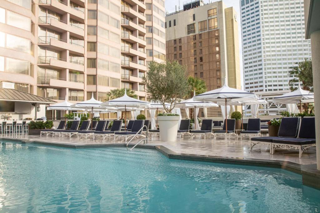 una piscina con sillas y sombrillas en un edificio en The Windsor Court en Nueva Orleans