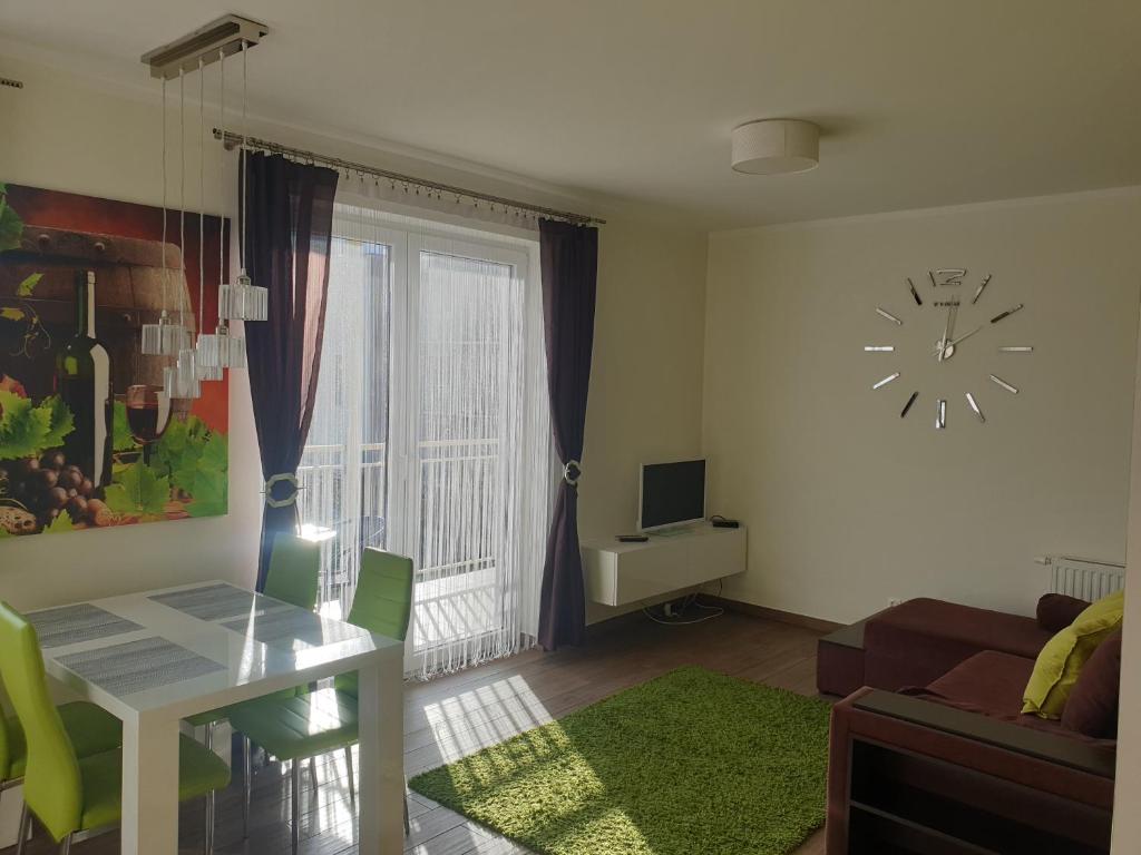 a living room with a table and a clock on the wall at Apartament Oliver in Darlowko