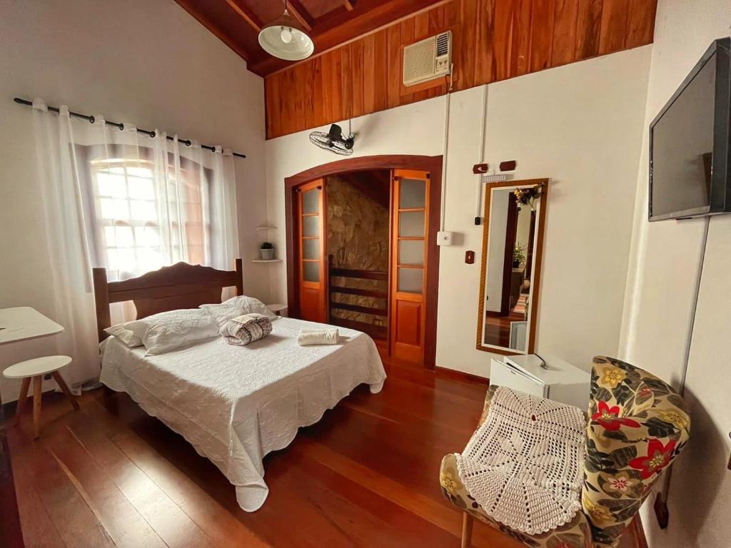 - une chambre avec un lit et une chaise dans l'établissement Casarão Paraty, à Parati