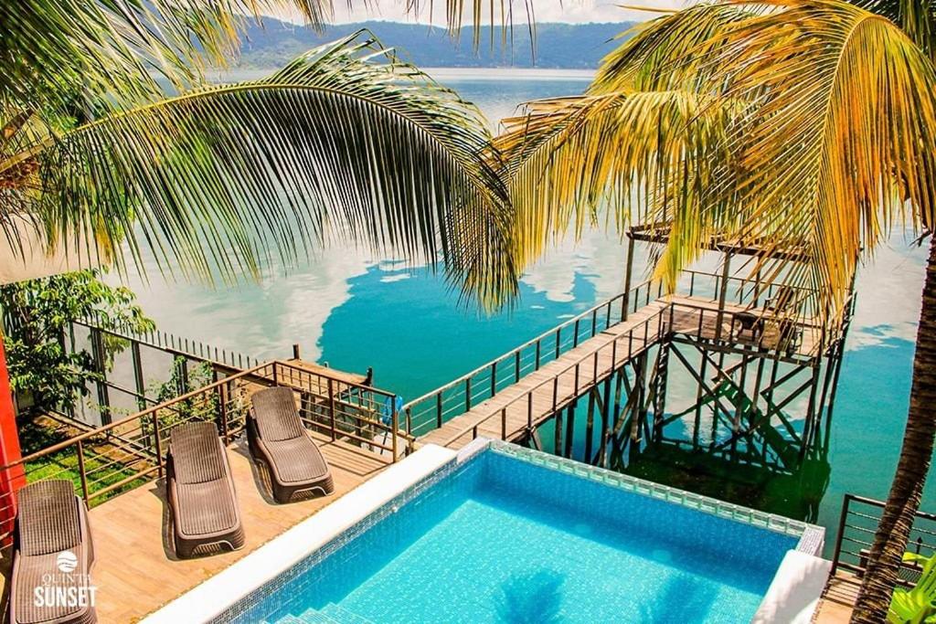 a swimming pool with chairs and a view of the water at Quinta Sunset, Lago de Coatepeque in El Congo