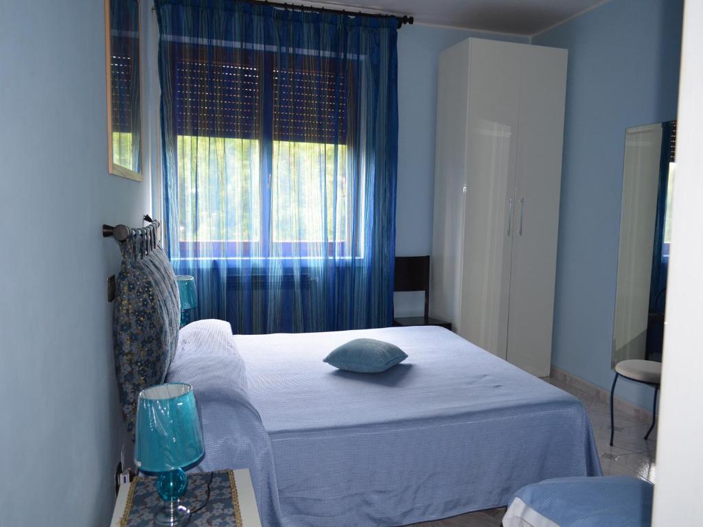 a bedroom with a bed and a window with blue curtains at A Casa di Carla in Terni