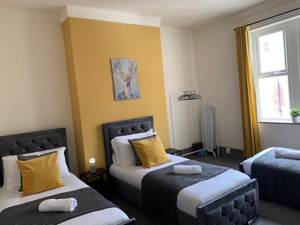 a bedroom with two beds with yellow walls at Balfour - Beautiful refurbished spacious 3 bedroom Gateshead flat in Gateshead
