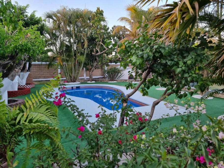 una piscina in un giardino con alberi e fiori di QuintaRosita a El Estudiante