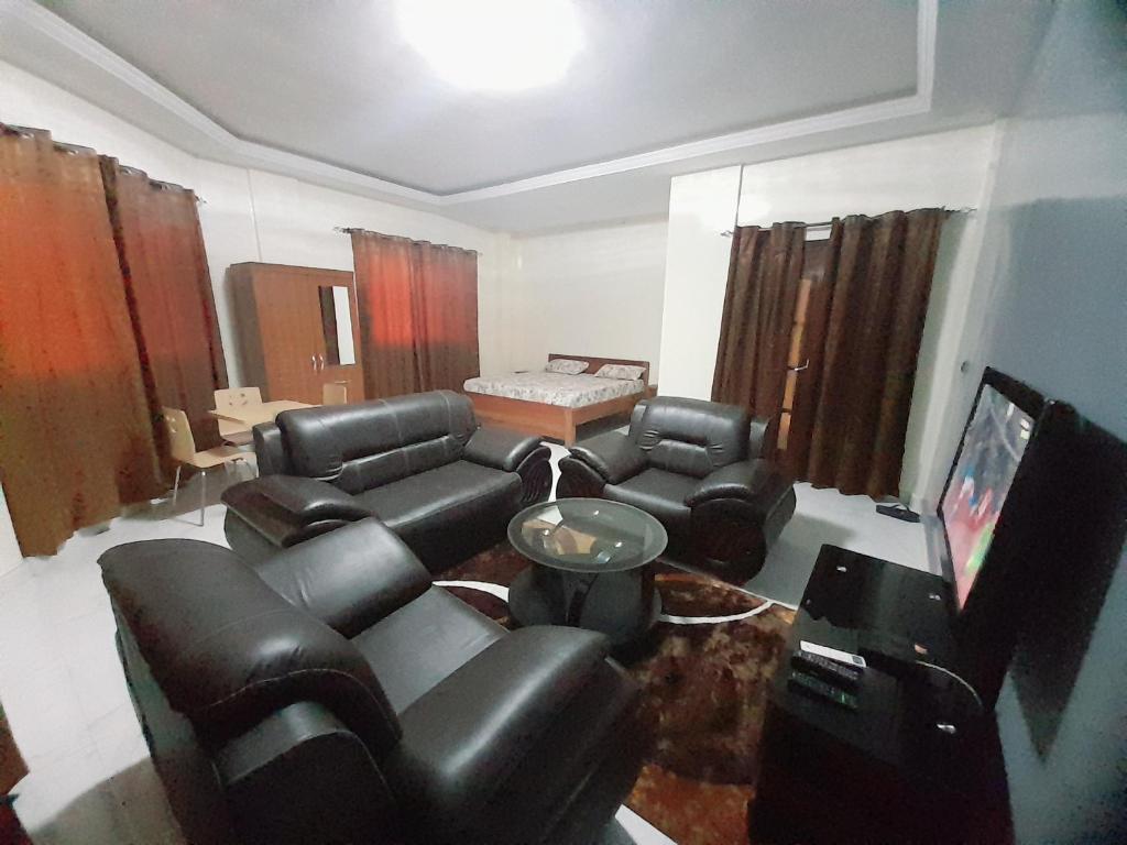 a living room with black leather furniture and a flat screen tv at Appartement meublé à Saint-Louis in Saint-Louis