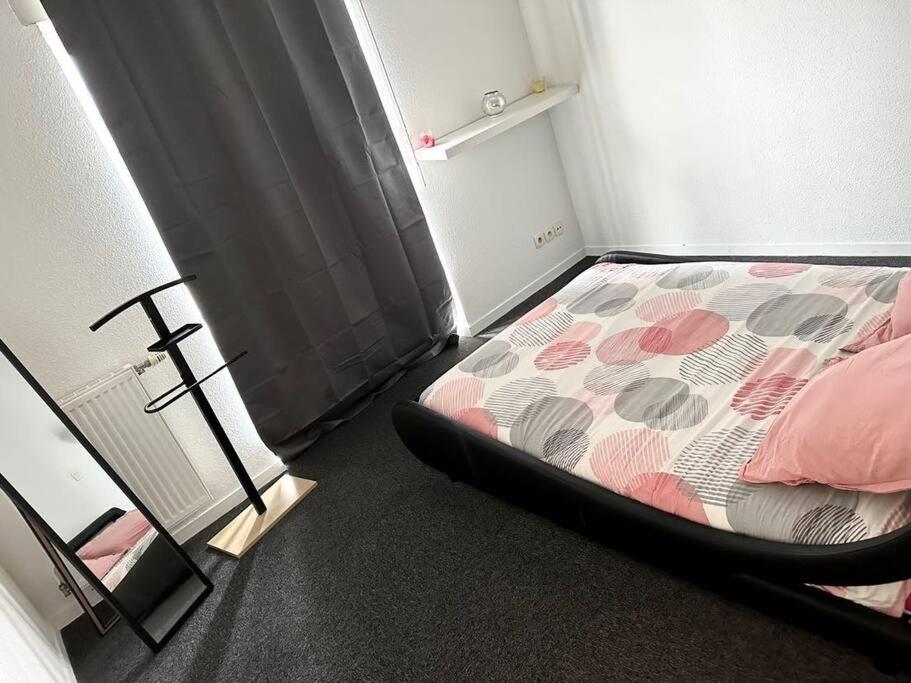um quarto com uma cama com lençóis cor-de-rosa e cinza em Appartement t2 au chartrons em Bordéus