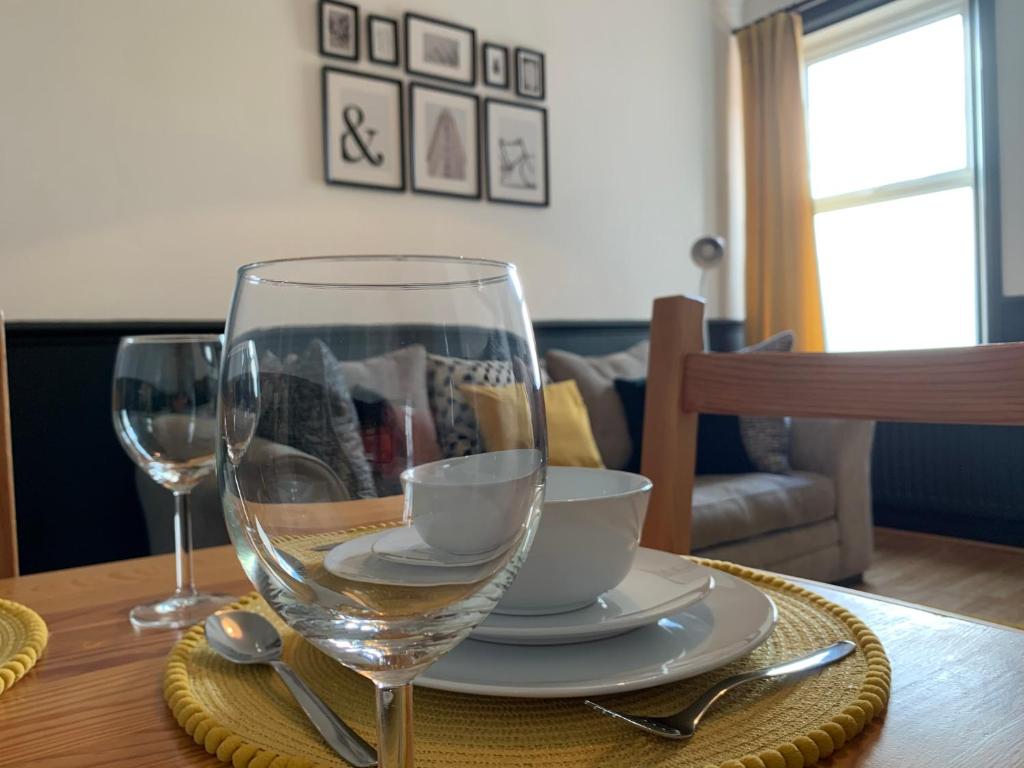 een tafel met een wijnglas en een bord en lepel bij Faraday - Central location Ideal for contractors and visiting Newcastle Free Wifi Free Parking in Gateshead