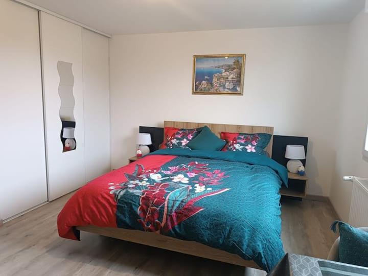 a bedroom with a bed with a red and blue blanket at Chambre privée in Montaigu-Vendée