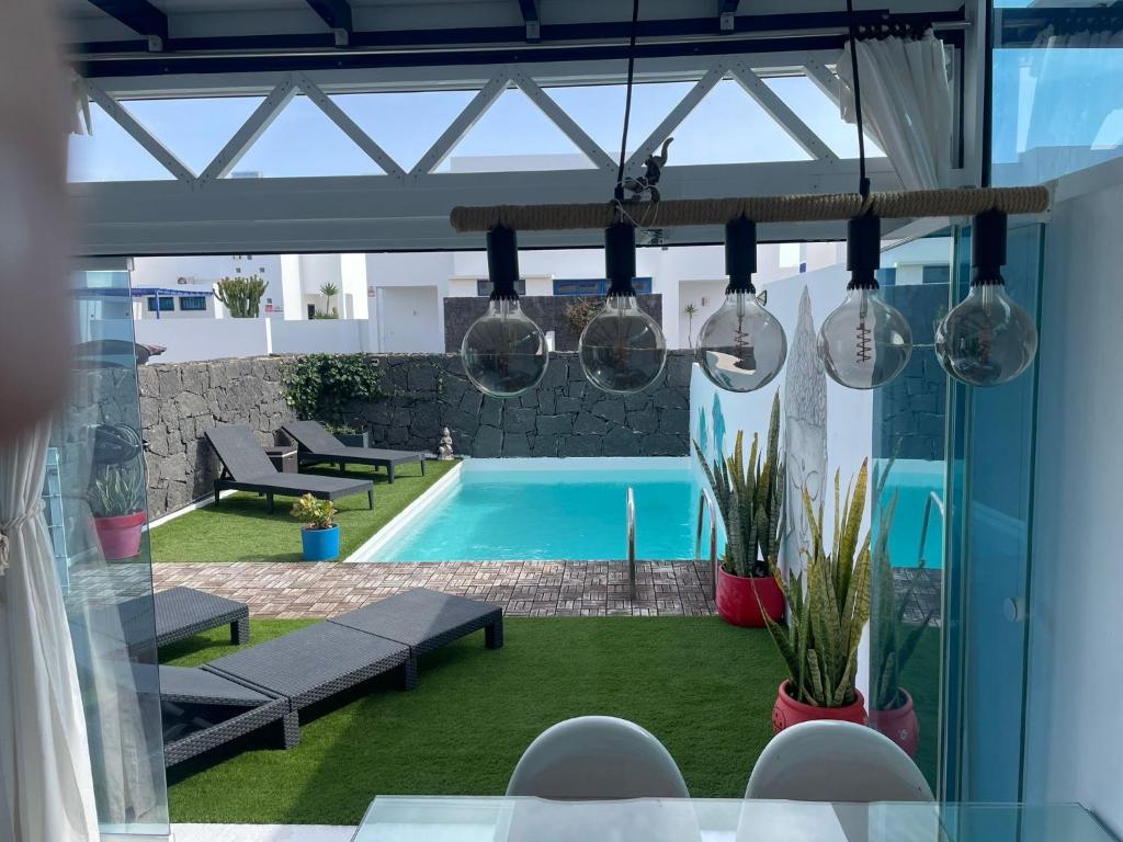 uitzicht op een zwembad vanaf een terras met hanglampen bij Villa Eclips in Playa Blanca