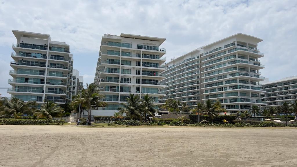 two tall buildings with palm trees in front of a beach at Apartamento Cartagena in Cartagena de Indias