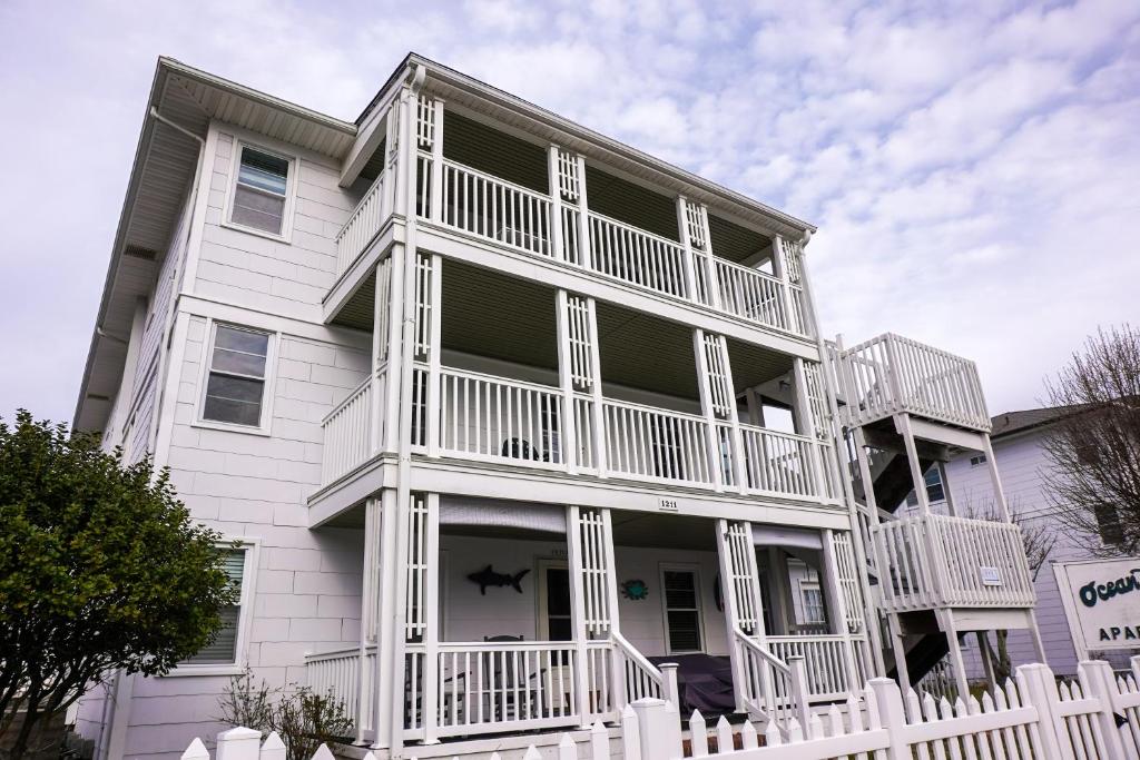 ein weißes Haus mit einem weißen Zaun davor in der Unterkunft Ocean Terrace Family Apartments in Ocean City