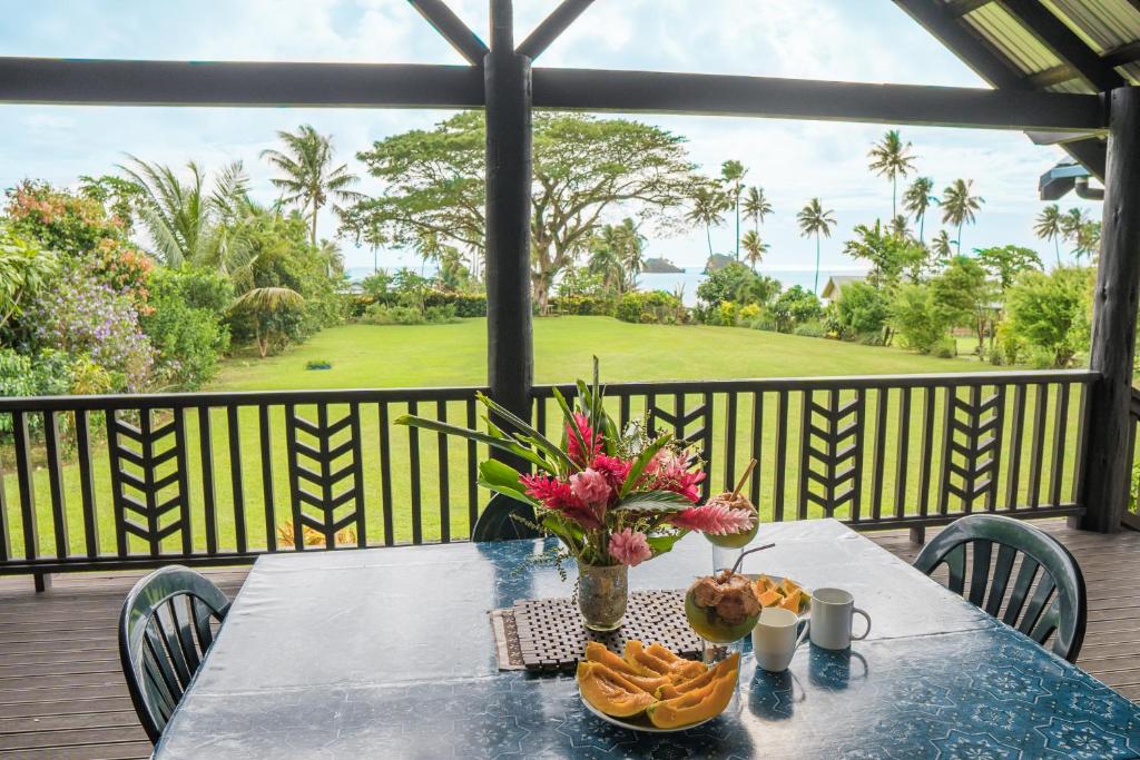 a table with a vase of flowers and chips on a balcony at Raintree Gardens - 1 Acre, Ocean Views, Steps from beach in Matei
