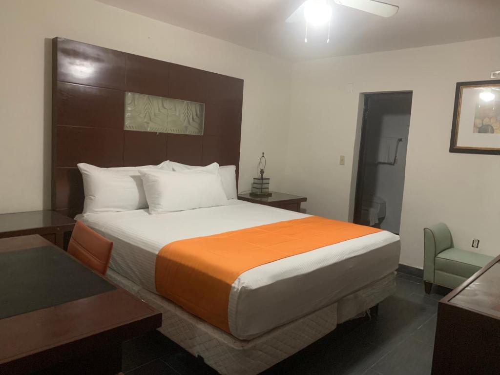 a bedroom with a large bed with an orange blanket at HOTEL DORADO DIAMANTE in Mexicali